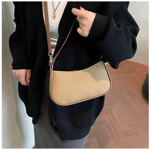 Detail of beige canvas baguette bag with brown leather trim and metallic buckle strap