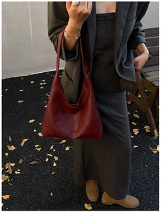 Close-up of deep burgundy leather tote bag with subtle texture and gold fashion logo