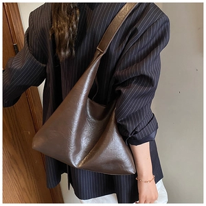Detail of a deep brown hobo bag in glossy faux leather showing texture and spacious design