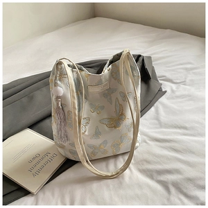 Détail de la broderie papillon bleu et or sur le sac cabas blanc avec pompon