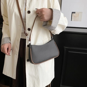 Chic black soft leather underarm bag with brown trim and silver hardware on a model