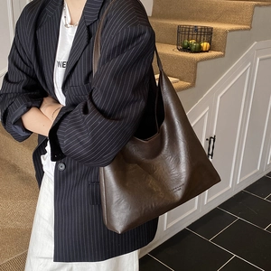 Large dark brown leather tote bag with vintage texture shown in a casual indoor setting