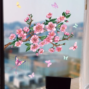 Dettaglio di vetrofanie con rami di fiori ad acquerello e farfalle colorate su vetro