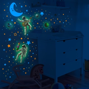 Glow-in-the-dark astronaut and stars wall stickers in a dark bedroom setting