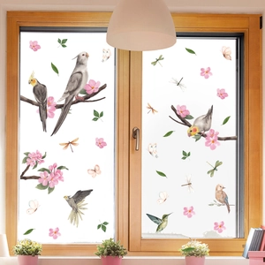 Detail of watercolor bird and floral window clings on a glass pane in a cozy room