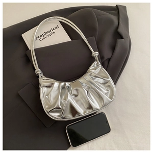 Detail view of silver pleated crescent bag with metallic finish and knotted strap