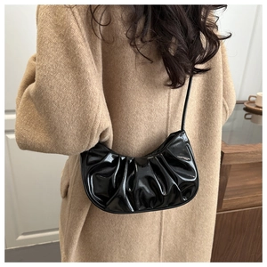 Detail of black glossy crescent shoulder bag with pleated texture on wool coat