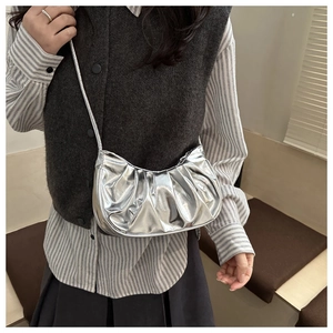 Detail view of silver crescent bag with ruched texture and metallic chain strap