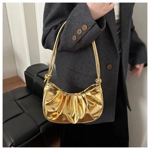 Detail of a metallic gold pleated hobo bag showing its liquid shine and knot strap detail