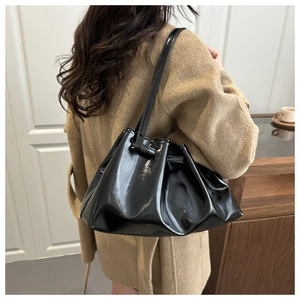 Fashionable black pleated bucket bag in glossy patent leather shown on model for daily commute