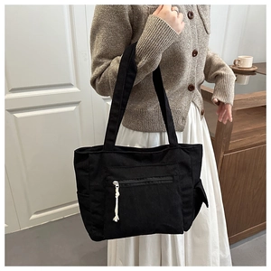 Détail du sac cabas en velours côtelé noir avec texture verticale et poche zippée