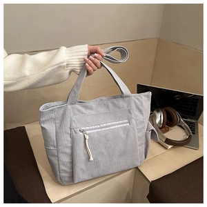 Détail du sac cabas en velours côtelé bleu-gris avec poche zippée à l'avant et compartiments