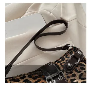 Detailed view of leopard print shoulder bag with silver hardware and brown leather strap
