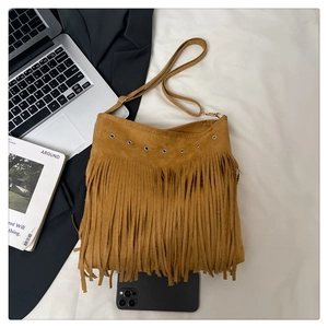 Détail du sac bohème en daim moutarde avec de longues franges et des œillets en métal