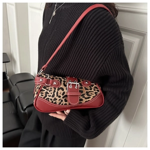 Detail der Leoparden-Unterachseltasche mit roten Lederriemen und Metallschnallen