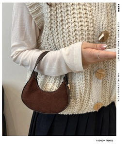 Close-up of retro dark brown matte suede crescent handbag styled on an autumn outfit