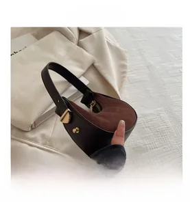 Detail view of dark brown suede crescent bag with gold buckles and zipper closure