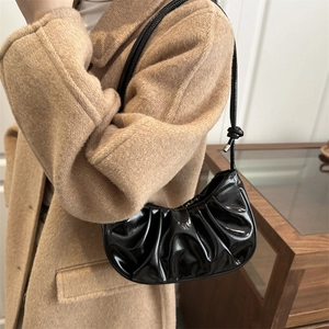 Minimalist black pleated moon bag made of glossy PU leather with knot strap details