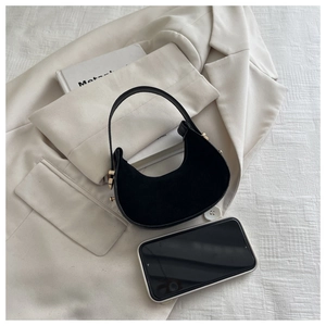 Mini black suede crescent handbag with gold hardware shown next to a smartphone
