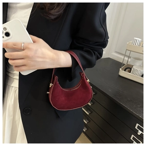 Close-up of burgundy suede hobo bag with gold metal rivets and semi-circular design