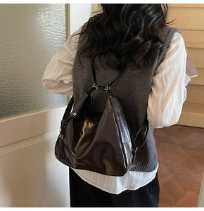 Detail of dark brown glossy hobo bag shown from back view on a female model