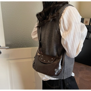 Dark brown shiny leather shoulder bag with silver rivet details worn by model