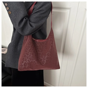 Detail of burgundy leopard print tote bag texture and slender shoulder strap on shoulder