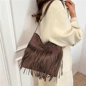 Sac à bandoulière marron à franges avec œillets porté sur un manteau beige élégant