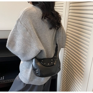 Detail of vintage black crescent shoulder bag with silver studs worn by a model