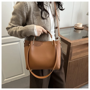 Dettaglio di una borsa marrone con motivo litchi, finiture dorate e tracolla sottile