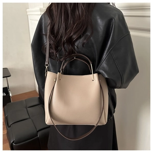 Detail of lychee pattern leather bucket bag in apricot with brown handles on model