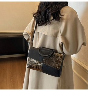 Detail of a chic snake-pattern crossbody bag worn with a classic trench coat