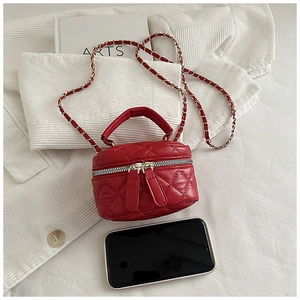 Macro view of burgundy quilted mini bag with gold chain and phone for scale