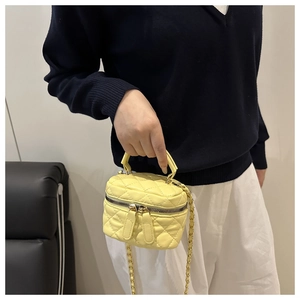 Detail of yellow quilted leather mini bag with gold chain strap and dual zippers
