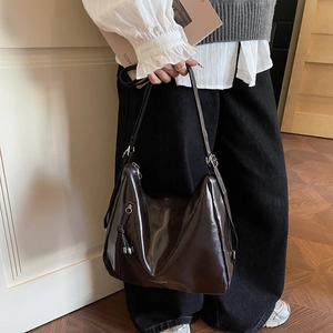 Deep brown glossy large tote bag with vintage texture shown on model in minimal setting