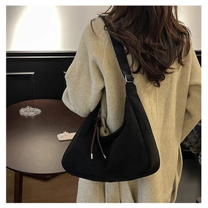 Close-up of black matte suede crescent bag with brown decorative cords and silver hardware
