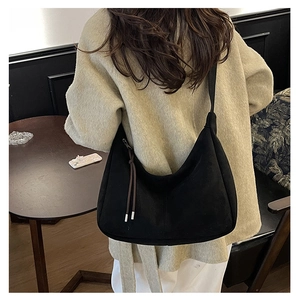 Detail of black faux suede crescent hobo bag with fringe zipper on a female model
