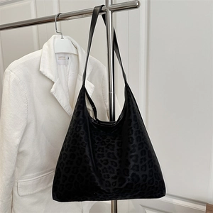 Large leopard print tote bag with black leather straps hanging on a metal rack