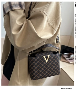 Macro detail of the vintage monogram pattern and golden V-shaped metal lock on the bag