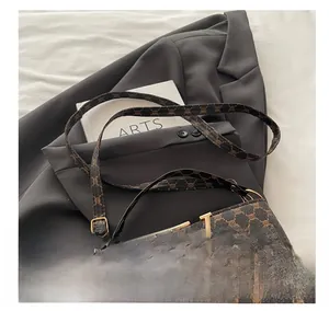 Detail view of vintage bucket bag with monogram pattern and gold V-buckle on a blazer