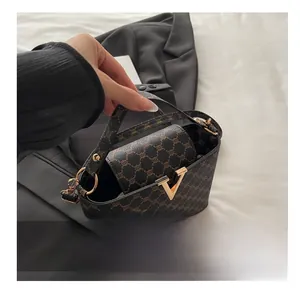 Close-up of brown monogram handbag featuring a prominent gold V-shaped metal clasp