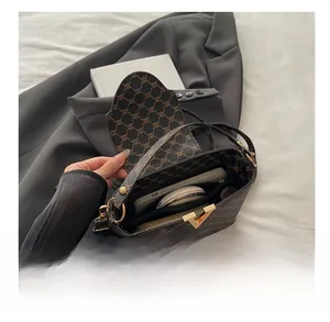 Detail view of spacious retro print crossbody bag showing interior with makeup items