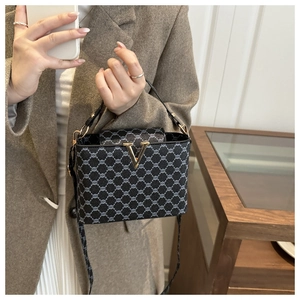 Detail of vintage geometric print handbag featuring gold V-shaped buckle and crossbody strap