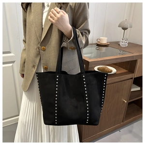 Macro shot of black suede tote bag featuring silver rivet studs and a spacious shoulder design