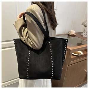 Detail of black suede tote bag with silver studs and wide shoulder strap on model