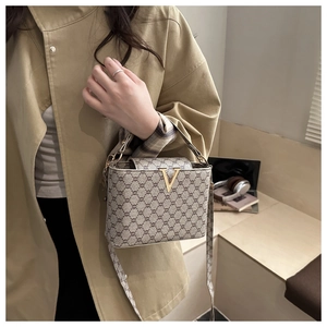 Detail of vintage brown printed crossbody bag with gold V-buckle on khaki coat
