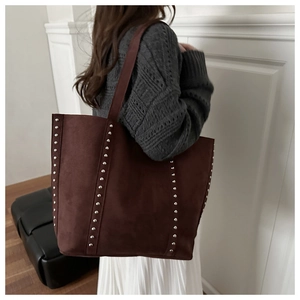Detailed view of dark brown suede tote bag featuring vertical silver rivet studs on shoulder