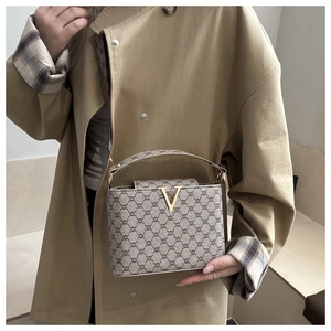 Detail view of a vintage monogram crossbody bag with a gold V-clasp on khaki coat