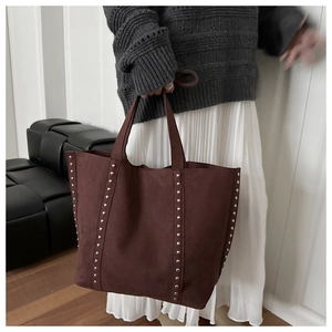 Close-up of vintage brown suede tote bag with silver rivets and dual handle details