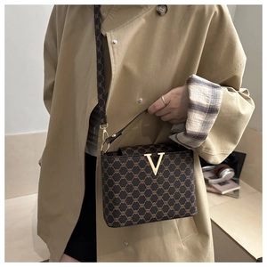 Detail of vintage tote bag with gold V hardware and adjustable strap on beige coat